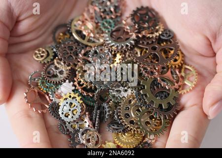 Ein Haufen verschiedener Metallgetriebe in menschlichen Händen, Nahaufnahme. Stockfoto