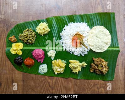 Traditionelle südindische Speiseplatte mit Reis und anderen abwechslungsreichen Speisen, serviert auf einem Bananenblatt für ein Festival oder einen Anlass Stockfoto