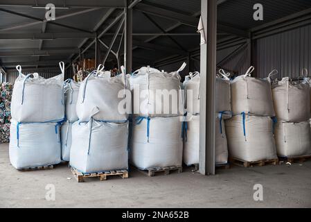 Riesige Plastiktüten mit Produkten auf Paletten in der Recyclingfabrik Stockfoto