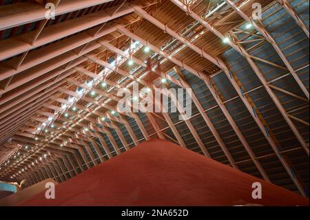 Gießen von roten Phosphatdüngern auf Stapel im Lagerhaus Stockfoto