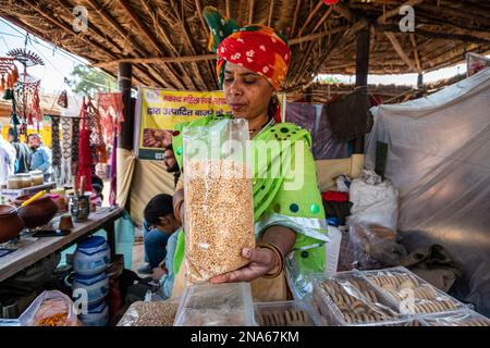 Auf der Surajkund International Crafts Fair in Faridabad im Jahr 36. bewerbt und präsentiert eine Ladenbesitzerin Snacks von Millet Grain (das Jahr 2023 wurde von den Vereinten Nationen zum Internationalen Jahr der Millet erklärt). Die Surajkund Mela (Messe) ist eine der berühmtesten und berühmtesten melas (Messen) in Indien. Sie findet jedes Jahr in der ersten Hälfte des Monats Februar in Faridabad statt. Dies ist eine der berühmtesten internationalen Handwerksmela (Messe) und wird vom Tourismusministerium des Bundesstaates Haryana organisiert. Stockfoto