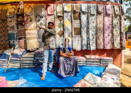 Ein Ladenbesitzer aus dem Bundesstaat Gujarat verkauft während der 36. in Faridabad stattfindenden Surajkund International Crafts Fair Quilts (Kutch Embroidery ist eine unverkennbare Textil- und Handwerkstradition der Stammesgemeinde Kutch). Die Surajkund Mela (Messe) ist eine der berühmtesten und berühmtesten melas (Messen) in Indien. Sie findet jedes Jahr in der ersten Hälfte des Monats Februar in Faridabad statt. Dies ist eine der berühmtesten internationalen Handwerksmela (Messe) und wird vom Tourismusministerium des Bundesstaates Haryana organisiert. Stockfoto