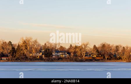 Kendrick Lake Park in Denver, Colorado. Eissee bei Sonnenuntergang mit Häusern am Ufer Stockfoto