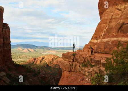 Eine junge Touristin fotografiert ihren Wanderpartner mit einem Handy, während er über den Sedona Canyon blickt; Sedona, Arizona, USA Stockfoto