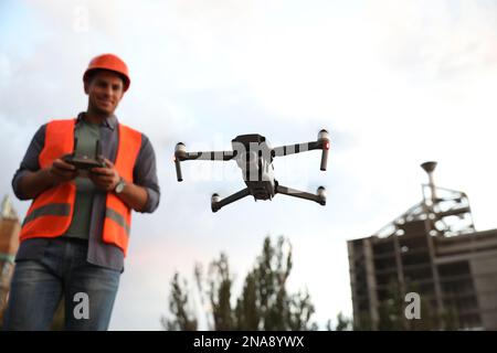 Bauarbeiter, die Drohne mit Fernsteuerung auf der Baustelle bedienen. Luftaufnahmen Stockfoto