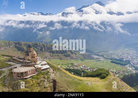 Aus der Vogelperspektive der Gergeti Trinity Church mit Blick auf die Städte Gergeti und Stepantsminda; Gergti, Kazbegi, Georgien Stockfoto