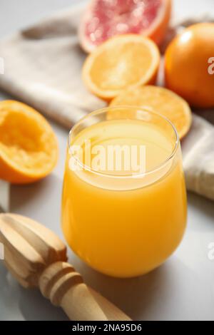 Frisch zubereiteter Saft, Orangen und Reibahle auf hellgrauem Tisch Stockfoto