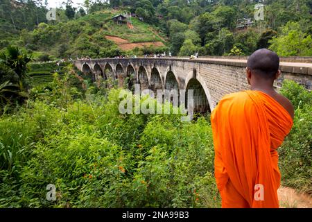 Buddhistischer Mönch in Safran an der Nine Arch Bridge zwischen Ella und Demodra, Hill Country, Sri Lanka; Ella, Badulla District, Sri Lanka Stockfoto