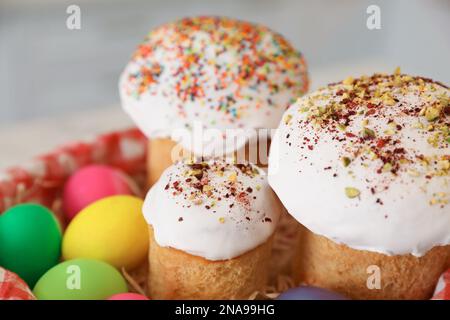 Traditionelle Osterkuchen und gefärbte Eier auf verschwommenem Hintergrund, Nahaufnahme Stockfoto