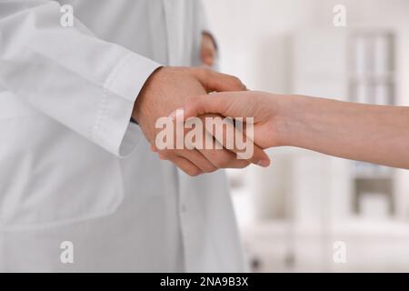 Die Ärzte grüßen die Frau mit einem Händedruck in der Klinik, Nahaufnahme Stockfoto