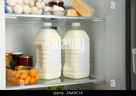 Gallonen Milch und verschiedene Produkte im Kühlschrank, Nahaufnahme Stockfoto