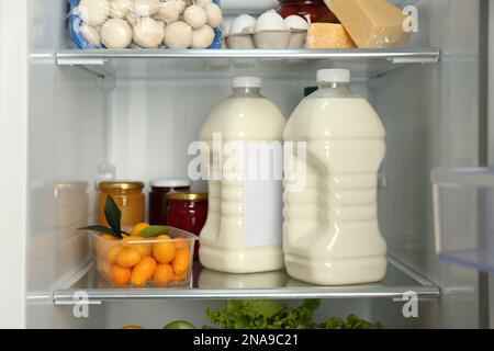 Gallonen Milch und verschiedene Produkte im Kühlschrank, Nahaufnahme Stockfoto