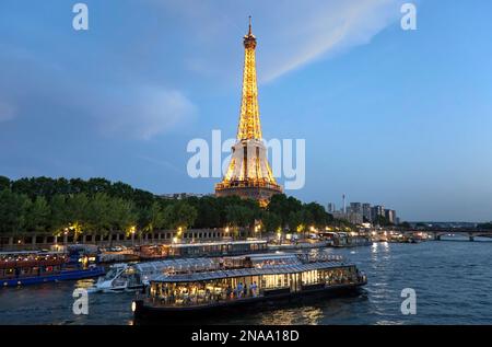 Eiffelturm beleuchtet bei Dämmerung und Flussboote auf der seine in Paris; Paris, Frankreich Stockfoto