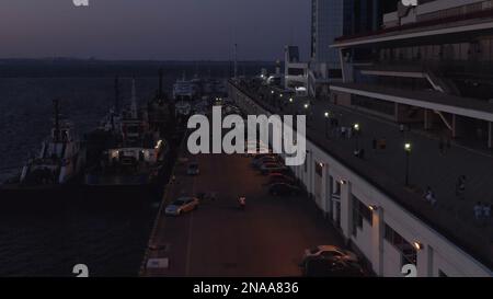 Kreuzfahrtschiffe und Autos am Seehafen bei Nacht. Stromausfall in Odessa, Ukraine. Abenddämmerung am Himmel. Stockfoto