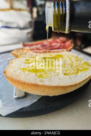 Ich gieße Olivenöl über die frisch zubereitete Toastscheibe. Selektiver Fokus Stockfoto