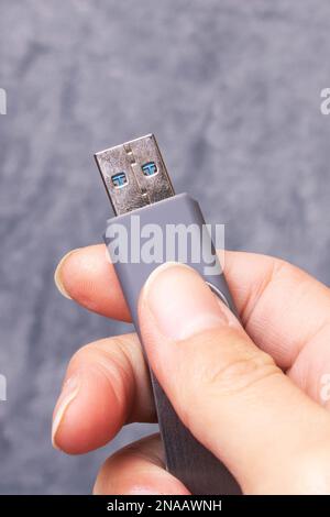 USB-Flash-Laufwerk in der Hand auf grauem Hintergrund Stockfoto