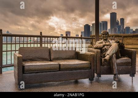 Bob Newhart Statue am Navy Pier mit der Skyline von Chicago im Hintergrund; Chicago, Illinois, Vereinigte Staaten von Amerika Stockfoto