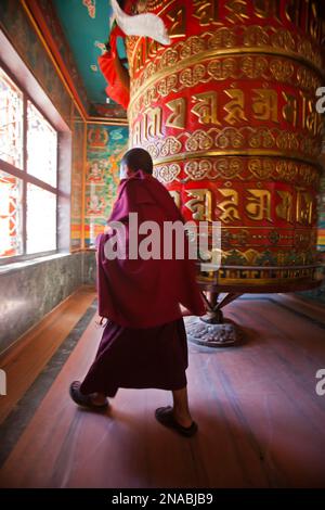 Ein Mönch spinnt das größte Gebetsrad der Welt in der Nähe von Boudhanath Stupa. Stockfoto