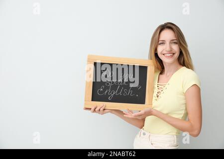 Junge Lehrerin mit Tafel und Wörtern Sprechen sie Englisch? Auf hellem Hintergrund. Platz für Text Stockfoto
