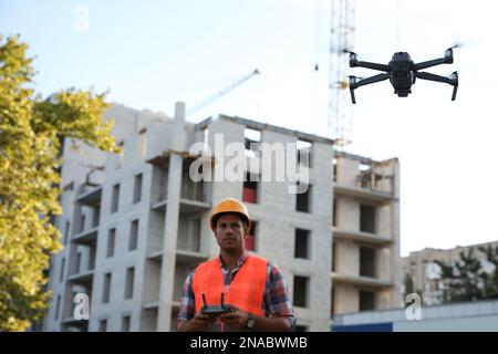 Bauarbeiter, die Drohne mit Fernsteuerung auf der Baustelle bedienen. Luftaufnahmen Stockfoto