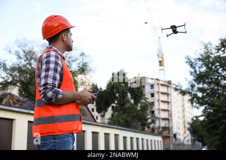 Bauarbeiter, die Drohne mit Fernsteuerung auf der Baustelle bedienen. Luftaufnahmen Stockfoto