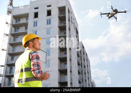 Bauarbeiter, die Drohne mit Fernsteuerung auf der Baustelle bedienen. Luftaufnahmen Stockfoto