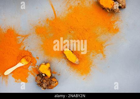 Kurkuma-Rhizome und Puder liegen flach auf Grau mit Kopierbereich Stockfoto