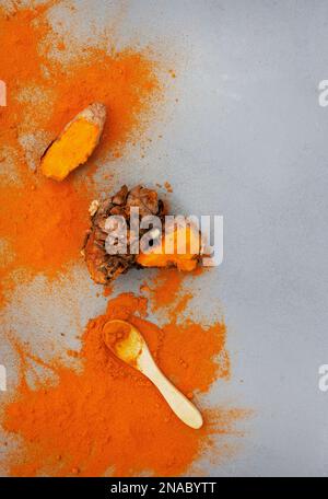 Kurkuma-Rhizome und Puder liegen flach auf Grau mit Kopierbereich Stockfoto