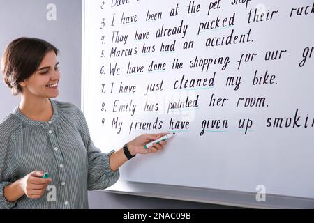 Glücklicher Englischlehrer beim Whiteboard im Unterricht Stockfoto