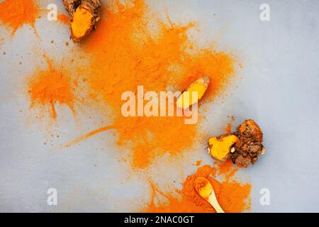 Kurkuma-Rhizome und Puder liegen flach auf Grau mit Kopierbereich Stockfoto