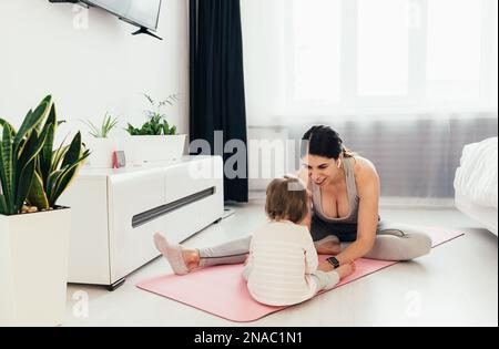 Mutter und Tochter Yoga zu Hause. Ein kleines Mädchen mit mom Stockfoto