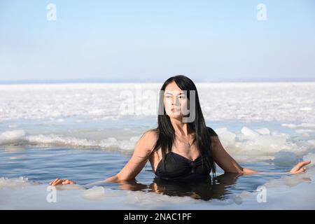 Frau, die am Wintertag in eiskaltes Wasser taucht. Taufe-Ritual Stockfoto