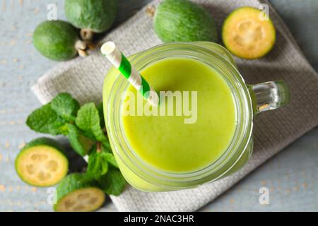 Flache Laienzusammensetzung mit frischem Feijoa Smoothie in Maurerglasflasche auf grauem Tisch Stockfoto