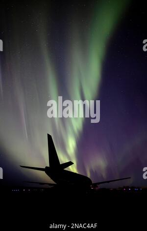 Silhouettenflugzeug mit Aurora Borealis am Sternenhimmel; Villeneuve, Alberta, Kanada Stockfoto