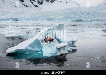 Besucher der Antarktis Cierva Cove, Teil von Graham Land auf der antarktischen Halbinsel, sehen ein Eisbergfragment in Form eines Bogens Stockfoto