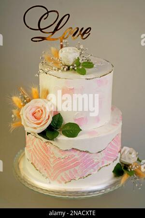 Hochzeitstorte mit frischen Blumen auf dunklem Hintergrund Stockfoto