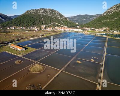 Draufsicht über die Salzpfanne in der Stadt Ston in Kroatien. Befestigte Mauern in den Hügeln im Hintergrund. Salzfelder. Ston Salt Arbeitet. Stockfoto