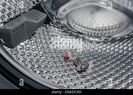 Metallgegenstände in der Waschmaschine, die die Waschmaschine beschädigen, wenn sie in den Taschen liegen. Haarspange, Haarrosa, Schlüssel, Münzen, Nagel, Schraube, Büroklammer. Stockfoto