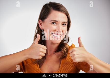 Es war so schön, dass ich es zweimal gezeigt habe. Studiofoto einer jungen Frau mit Daumen nach oben vor weißem Hintergrund. Stockfoto