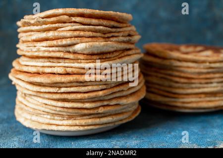 Fladenbrot Lavash, Chapati, Naan, ein Haufen Tortilla auf blauem Hintergrund hausgemachtes Fladenbrot gestapelt. Stockfoto