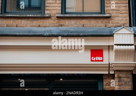 London, UK - 09. Februar 2023: Namensschild an der Fassade des Crisis Brick Lane-Shops. Der Laden wurde am 15. Dezember 2022 eröffnet, um Geld zu sammeln und das Geschäft zu unterstützen Stockfoto