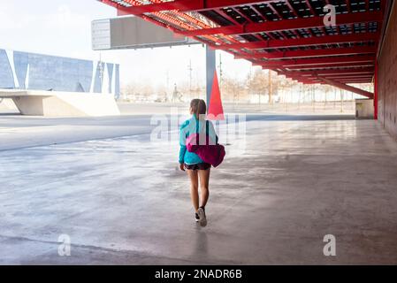 Sportlerin, die beim Gehen die Tasche hält Stockfoto