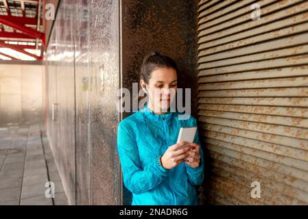 Portrait von schönen Sportlerin hält Handy Stockfoto