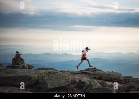 Ein Streuner, der auf dem Bergrücken mit Cairn und Bergen läuft Stockfoto