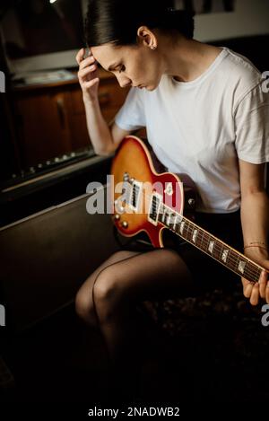 Einsames Mädchen mit einer elektrischen Gitarre in ihrem Zimmer Stockfoto