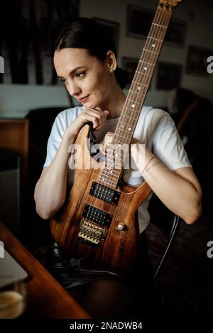 Nahaufnahme einer glücklichen Hipsterin mit ihrer E-Gitarre. Stockfoto