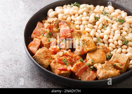 Weiße Bohnen mit gebratenem Schweinefleisch Freginat Nahaufnahme auf einem Teller auf dem Tisch. Horizontal Stockfoto