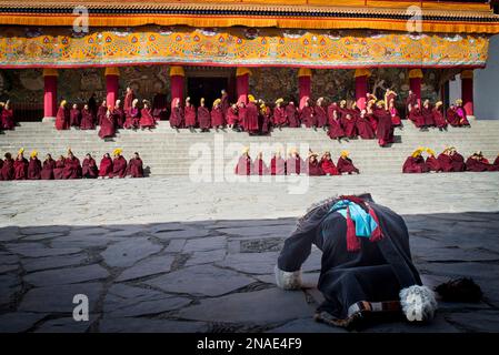 Buddhistischer Pilger, der sich vor dem Kloster mit Mönchen niederwirft; Labrang, Amdo, China Stockfoto