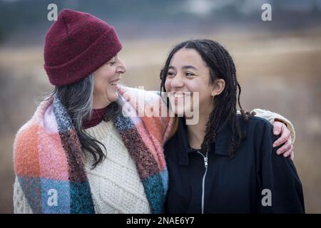 Weiße Mutter und birassische Teenager-Tochter, die sich anlächeln Stockfoto