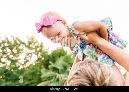 Dad wirft sein kleines Mädchen im Sommer draußen in die Arme Stockfoto